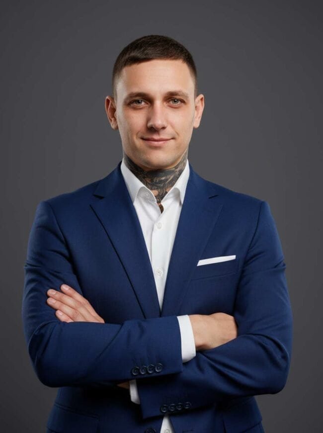 Confident man in professional suit with arms crossed, studio portrait for business profile.